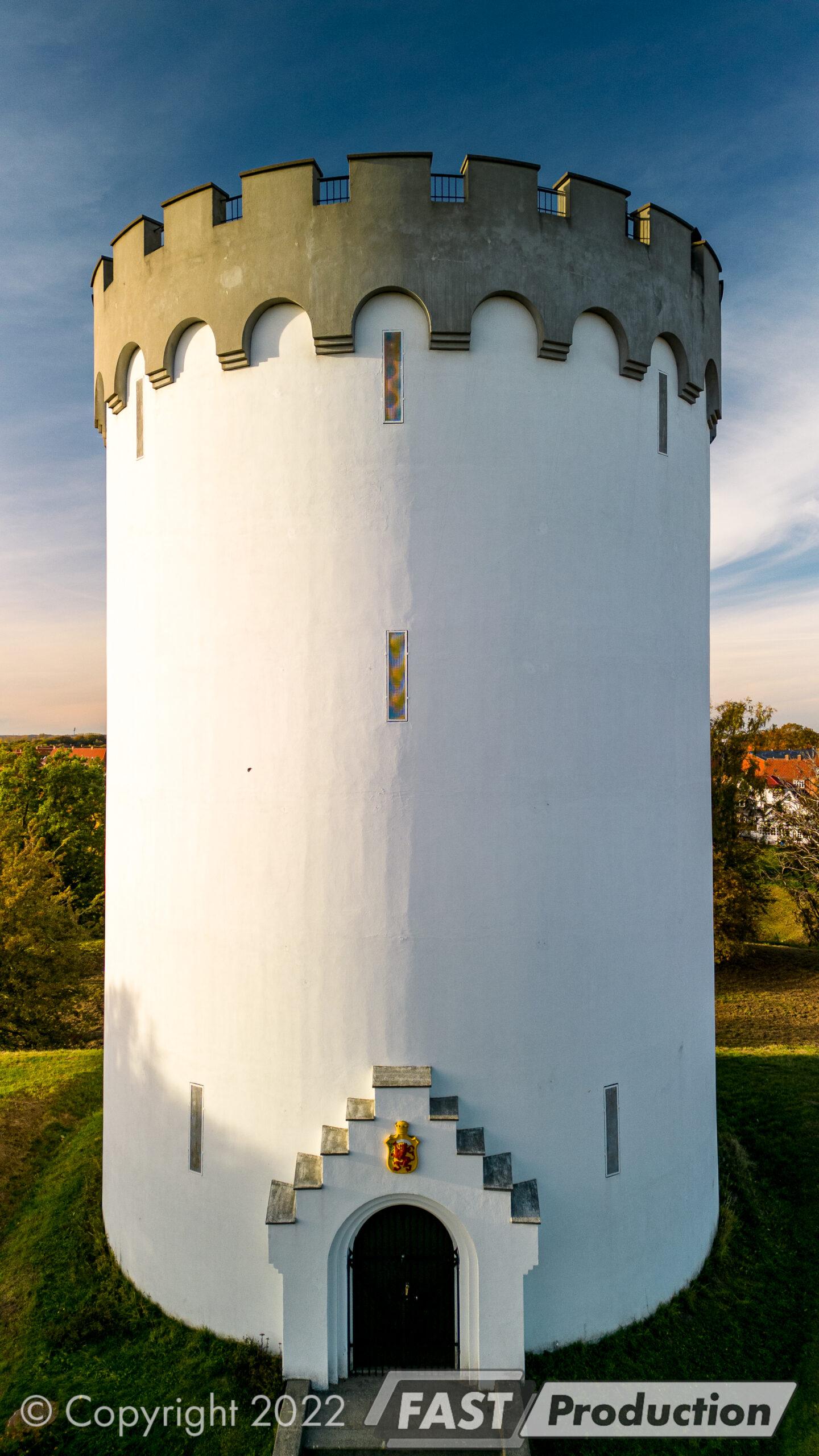Portrætformat dronefoto af Det Hvide Tårn med murkrone i varmt aftenlys