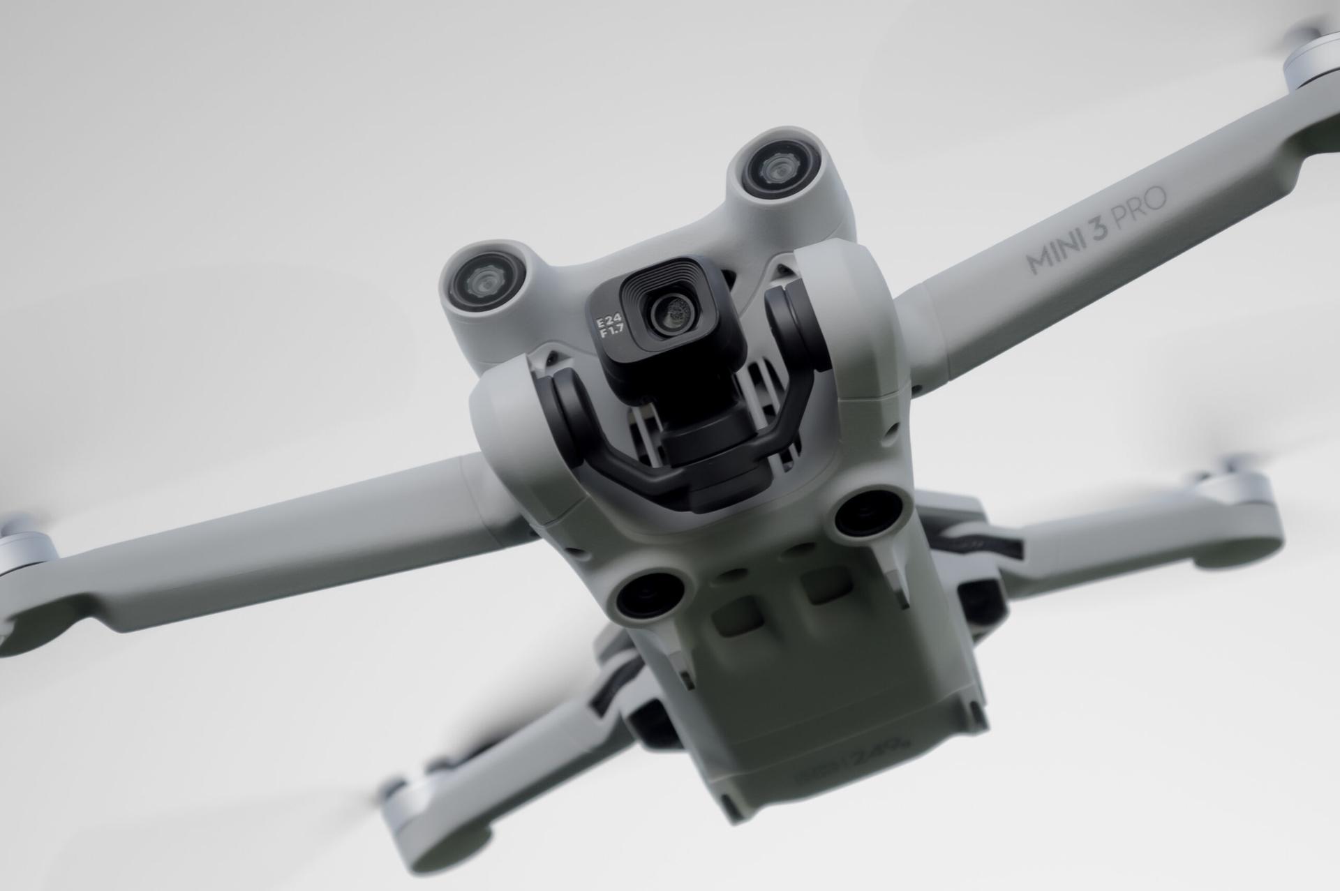 DJI Mini 3 Pro drone i luften, set nedefra mod en lys himmel